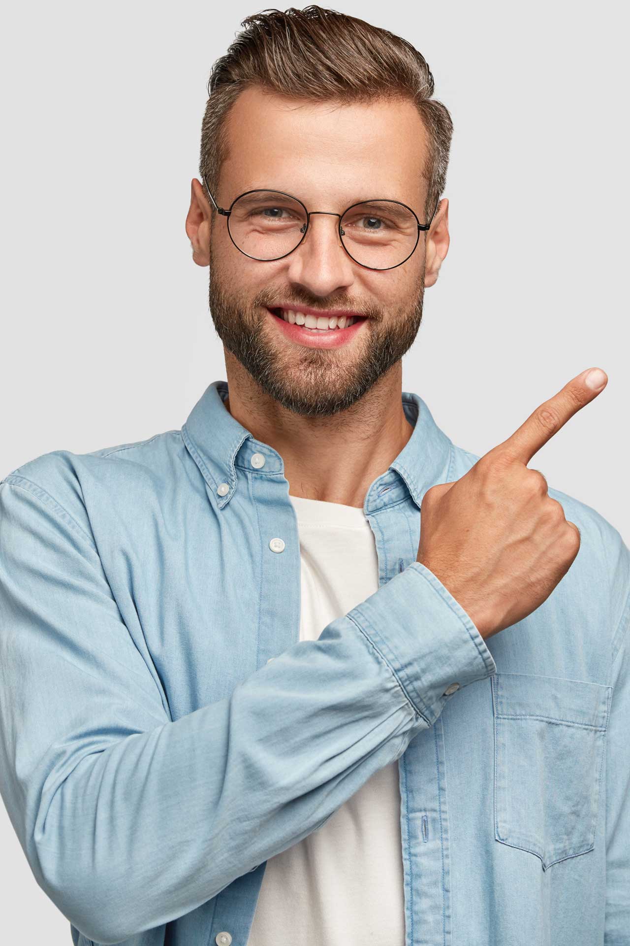 Man with facial hair, glasses, and a jean jacket smiling and pointing to the right