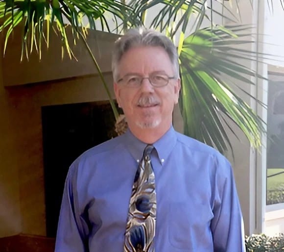 Man with gray hair, glasses, and a blue shirt